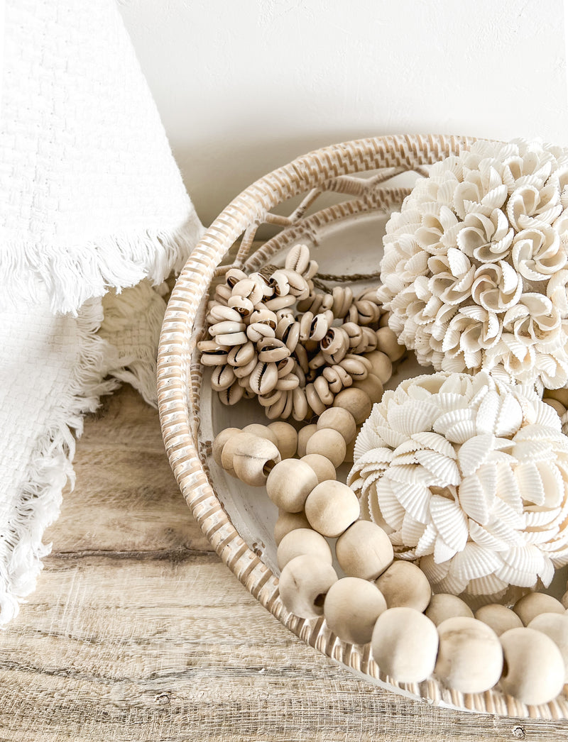 A cluster of natural cowrie shells carefully strung together from a braided Jute base.  These gorgeous tassels can hang from a wall hook, door knob or be draped over a shelf. Simply place on a stack of books on a side table, use over a decorative bowl or add to an existing centrepiece on your hall or coffee table.  