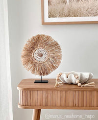 A centrepiece of curated feature shells surrounded by fringing of dried raffia creates this gorgeous table top decor piece.  The Lexi design has been inspired by our raffia juju wall hangings, only this one sits complete on a custom made stand.  Ideal for display on a console, side table, shelf or a picture ledge to level up your styling & keep a consistent flow throughout your home.