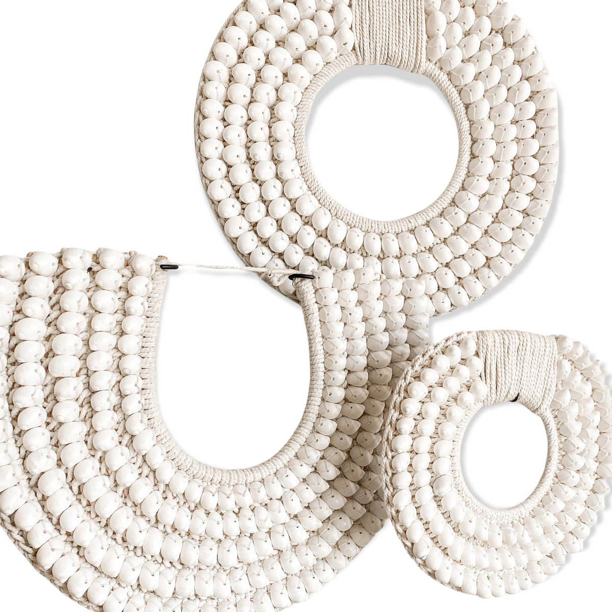 Smooth white shells, intricately sewn by hand onto a thick crochet backing. These authentic papua tribal shell necklaces are a versatile piece & will inject a coastal vibe into your space. Use as a wall hanging or mix & match sizes and styles to create a custom feature. Purchase with a custom made stand for use as a tabletop decor piece on a side table, vanity, console or shelf.  
